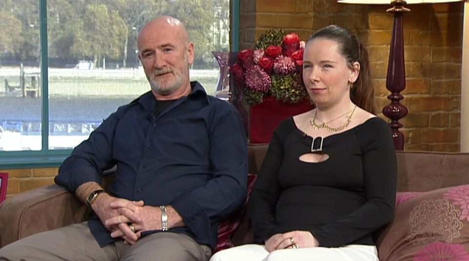 a man and a woman sit on a couch in front of a window