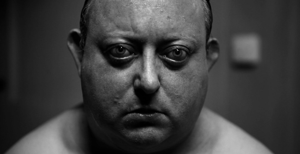 a black and white photo of a shirtless man looking at the camera