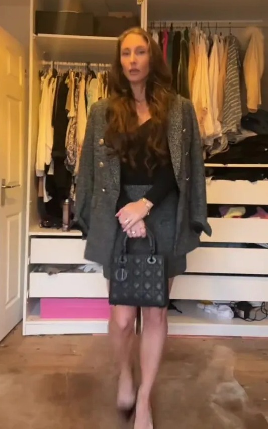 a woman is standing in front of a closet holding a black bag .