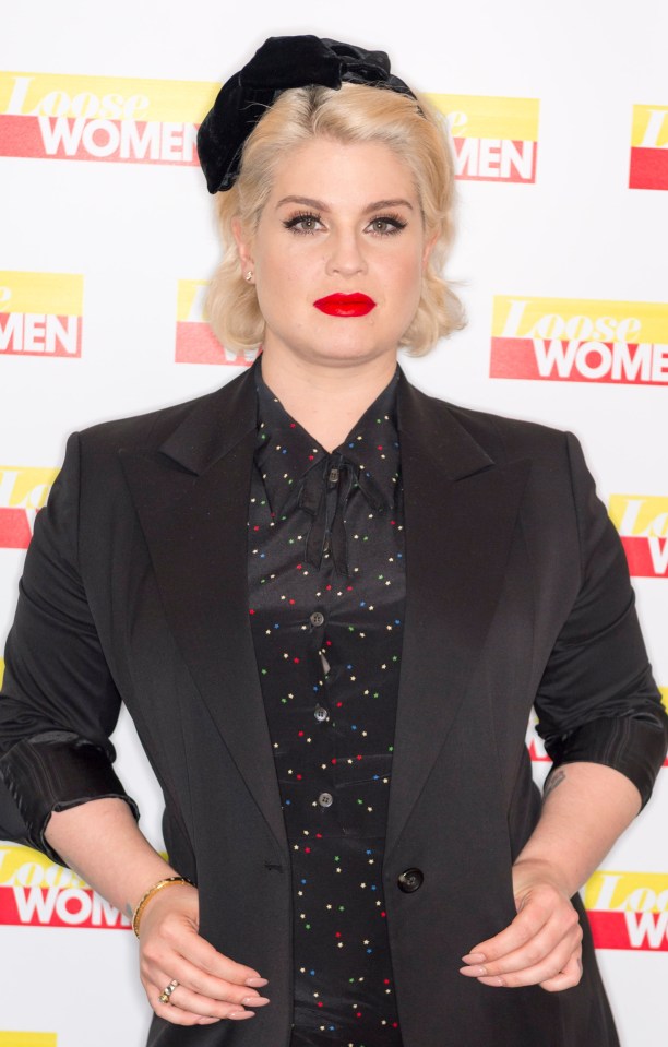 a woman stands in front of a sign that says loose women