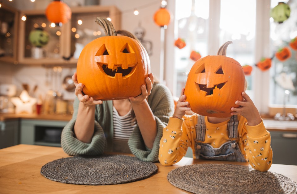 a woman and child holding pumpkins in front of their faces