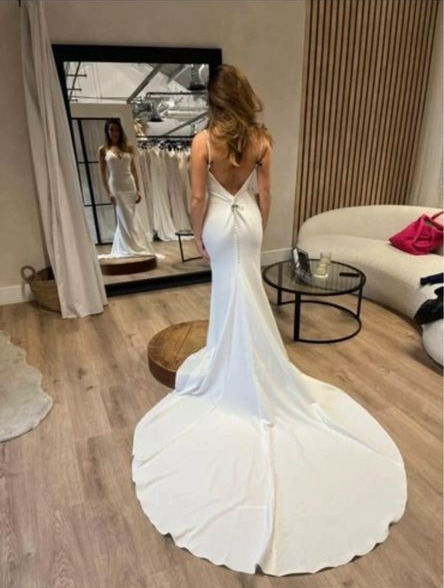 a woman in a white wedding dress is standing in front of a mirror .