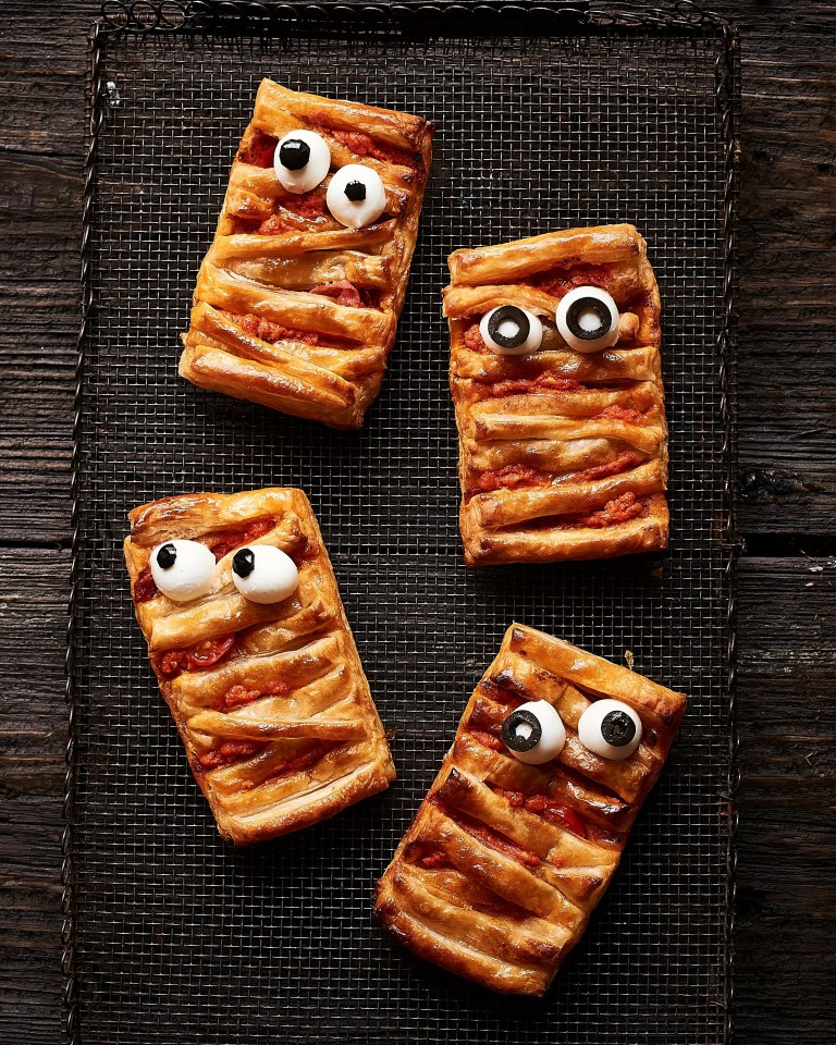 a tray of mummy shaped pastries with googly eyes