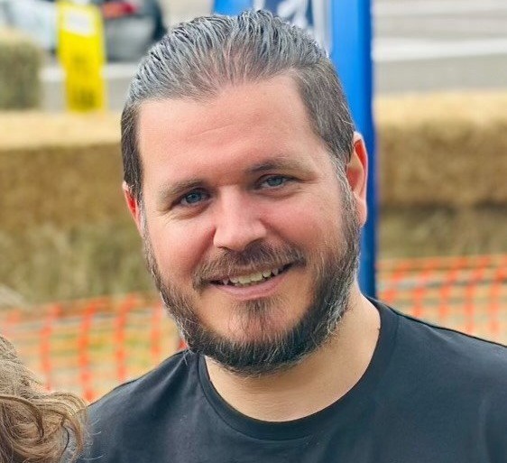 a man with a beard wears a black shirt with the word ford on it