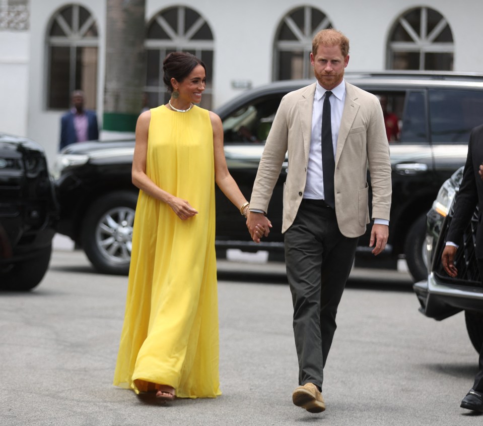 prince harry and meghan markle walk down the street holding hands