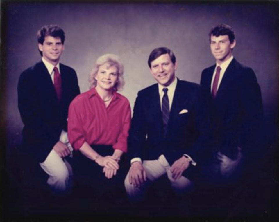 a family posing for a picture with two men in suits and a woman in a red shirt