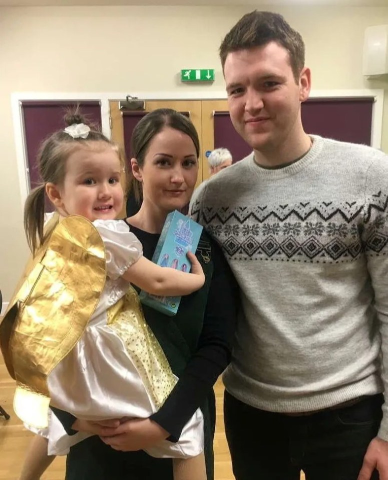 a man and a woman holding a little girl in front of a green exit sign