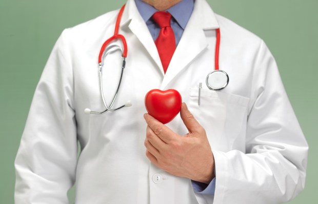 a doctor with a stethoscope around his neck holds a red heart