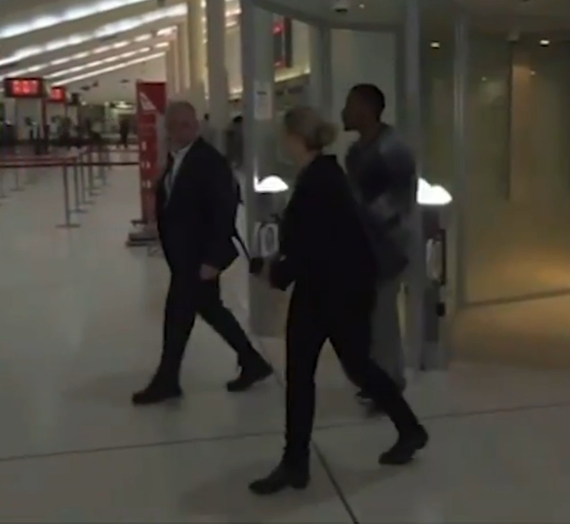 a man in a suit walks with a woman in front of a sign that says 10