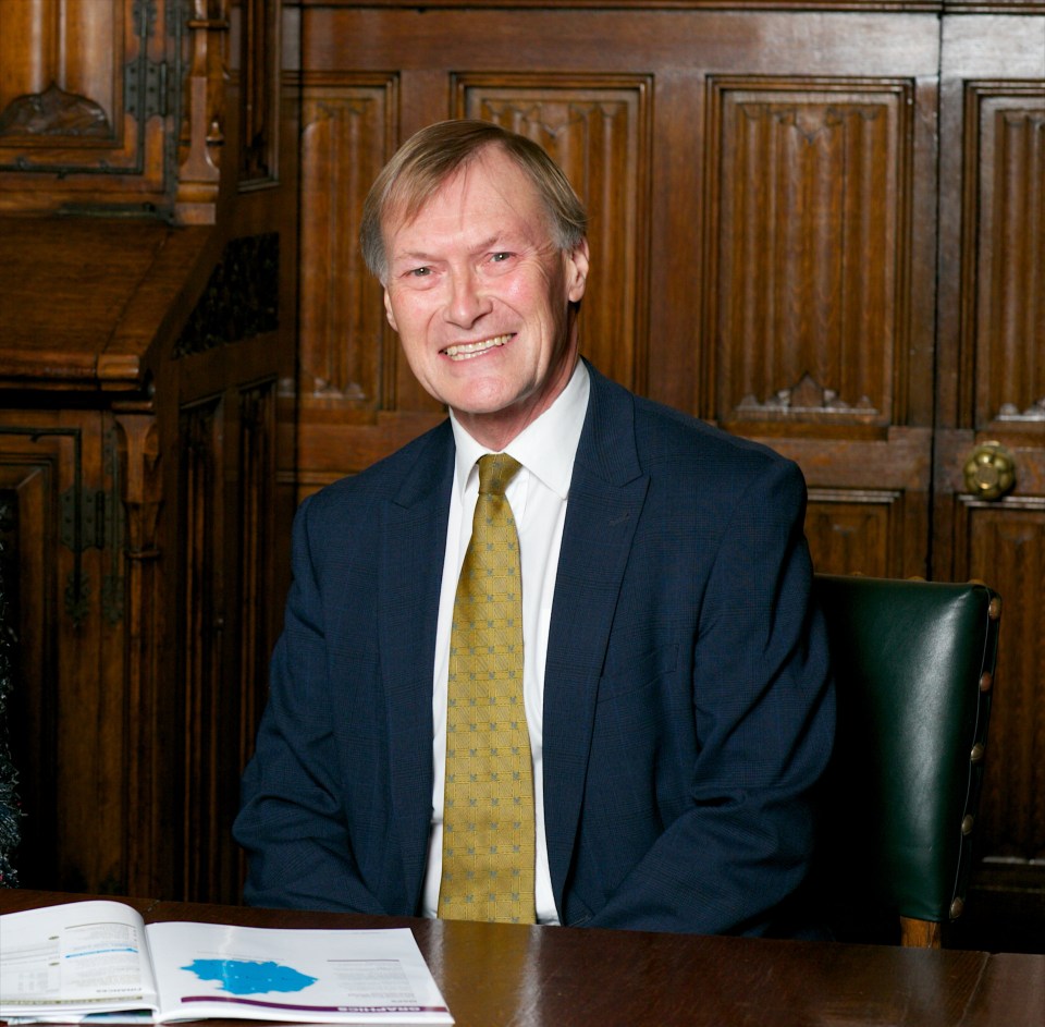 a man in a suit and tie sits at a desk