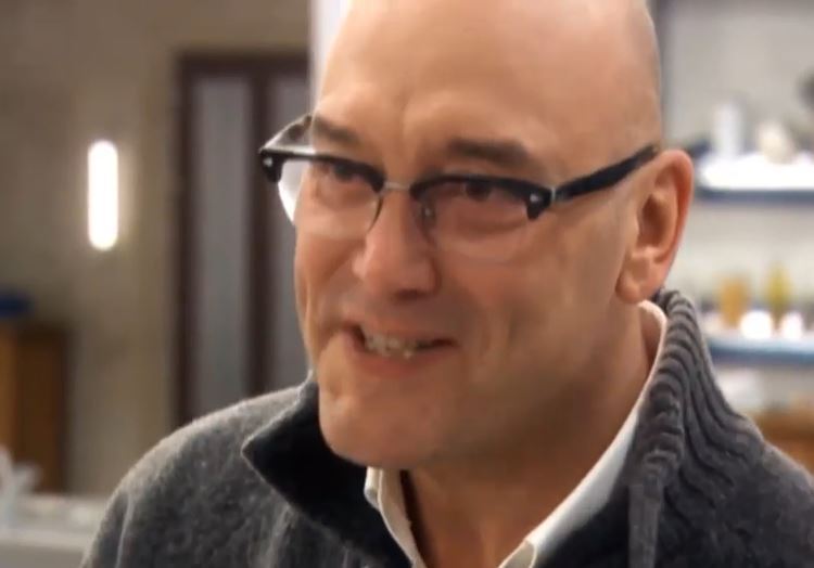 a bald man wearing glasses and a sweater is smiling .