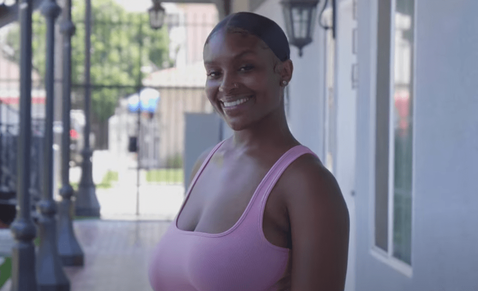 a woman in a pink tank top smiles for the camera