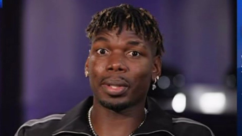 a close up of a man wearing a black jacket and earrings .