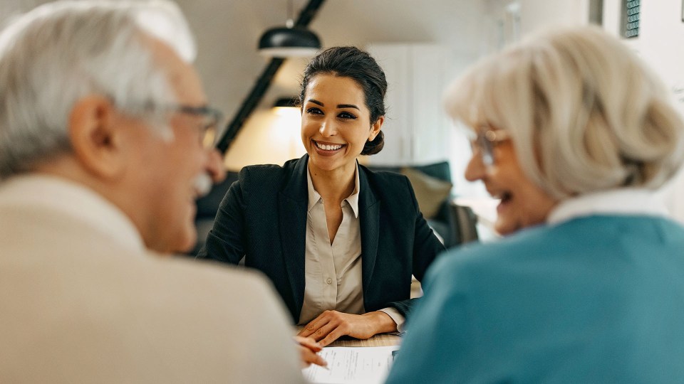 a woman is smiling while sitting at a table with two older people