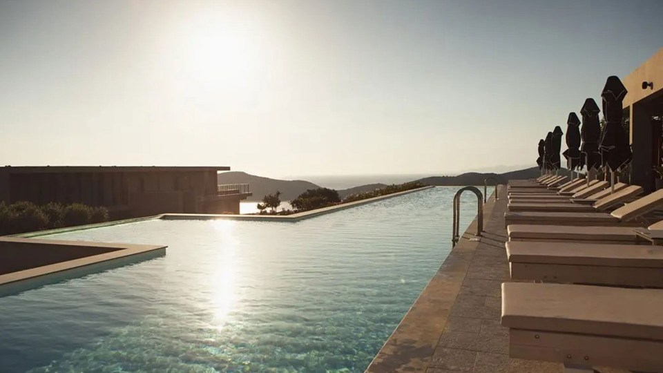 a large swimming pool surrounded by lounge chairs and umbrellas