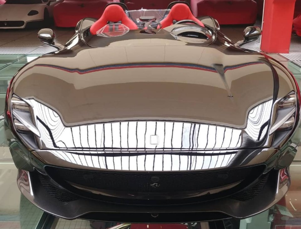 a black sports car with red seats sits on a glass floor