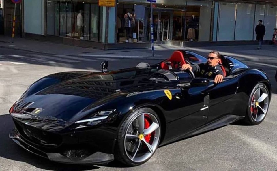 a man is sitting in a black sports car with the word ferrari on the side