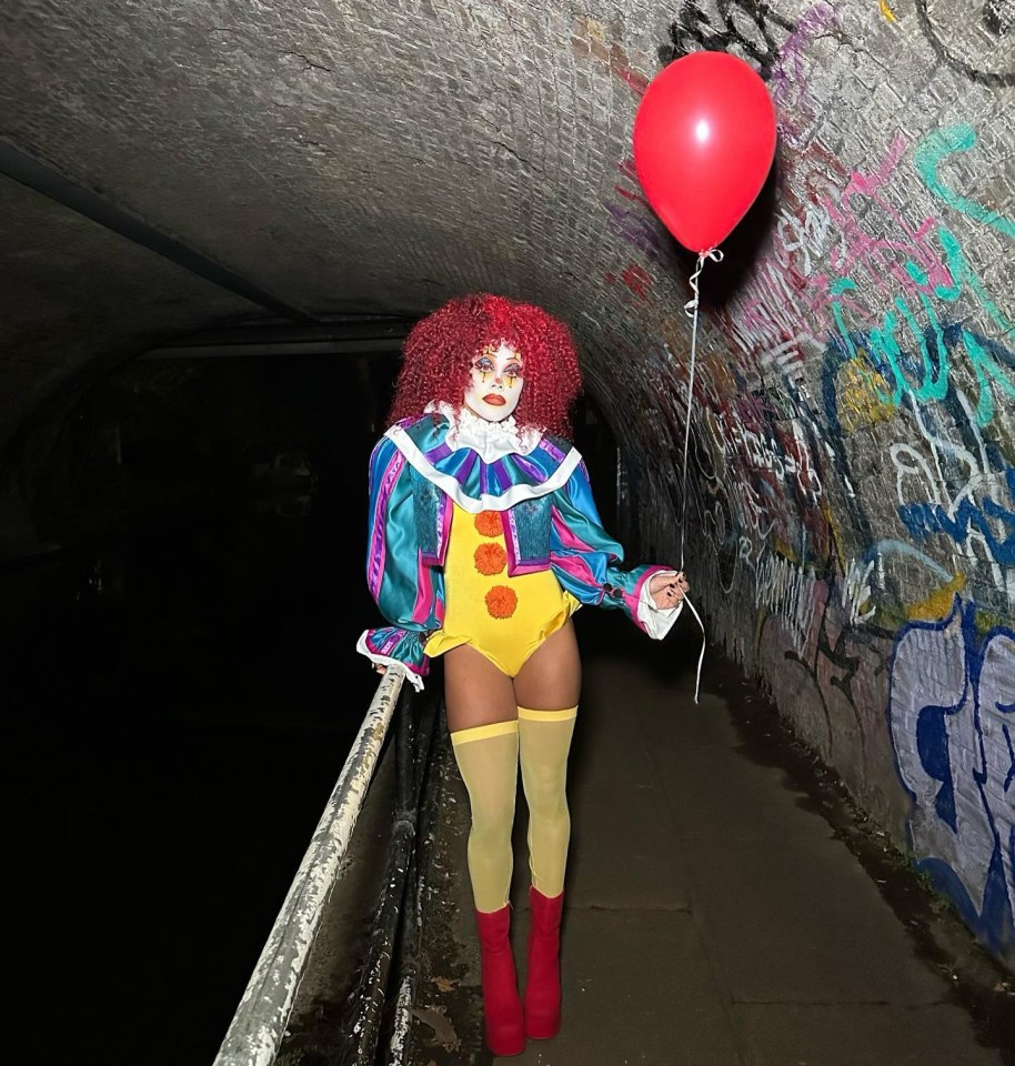 a woman dressed as a clown is holding a red balloon