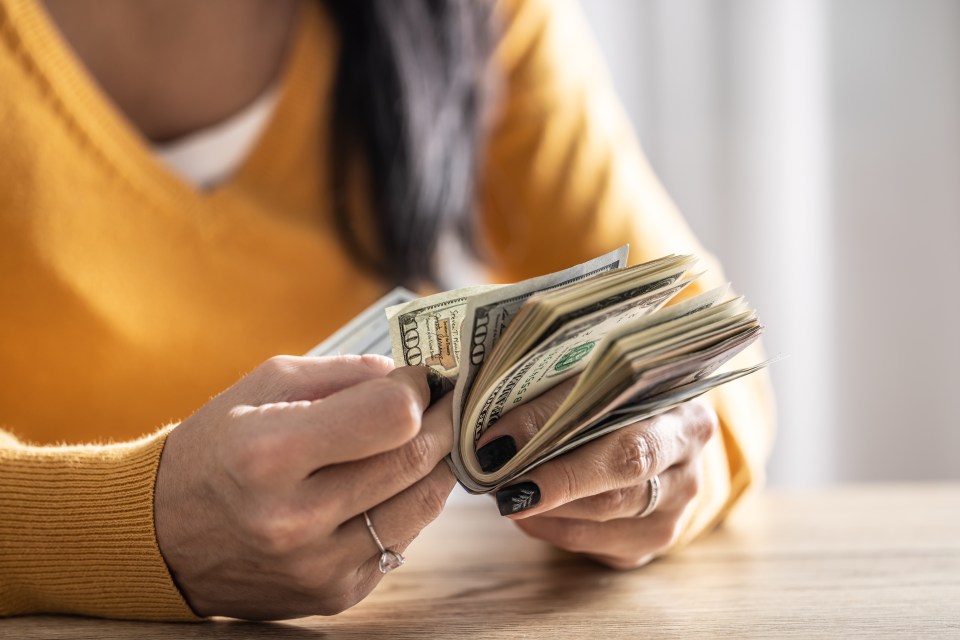 a woman is holding a stack of 100 dollar bills