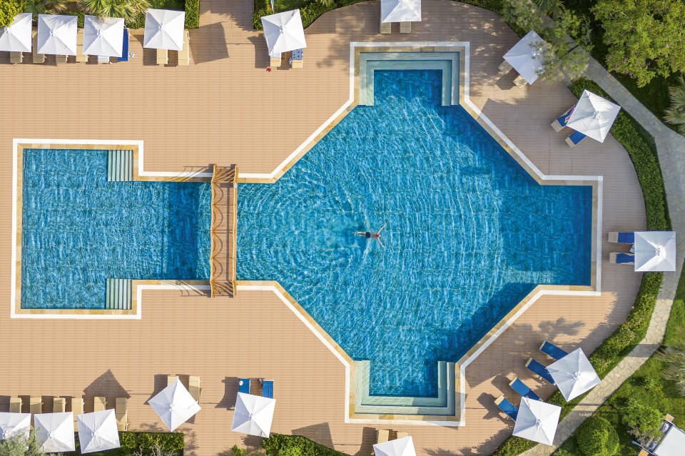 an aerial view of a large swimming pool surrounded by chairs and umbrellas