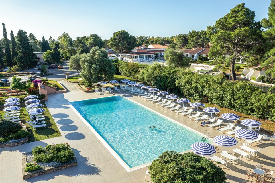 a large swimming pool surrounded by chairs and umbrellas