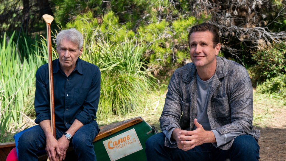 two men sit next to a canoe that says canoe rentals