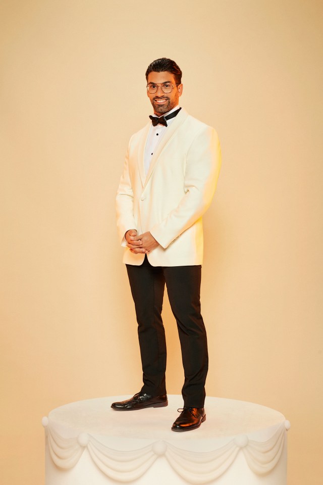 a man in a tuxedo stands on top of a white cake