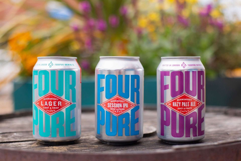 three cans of four pure beer sit on a wooden table