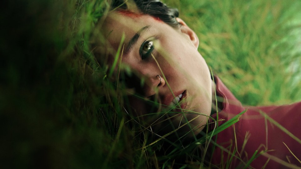 a woman with a nose ring is laying in the grass