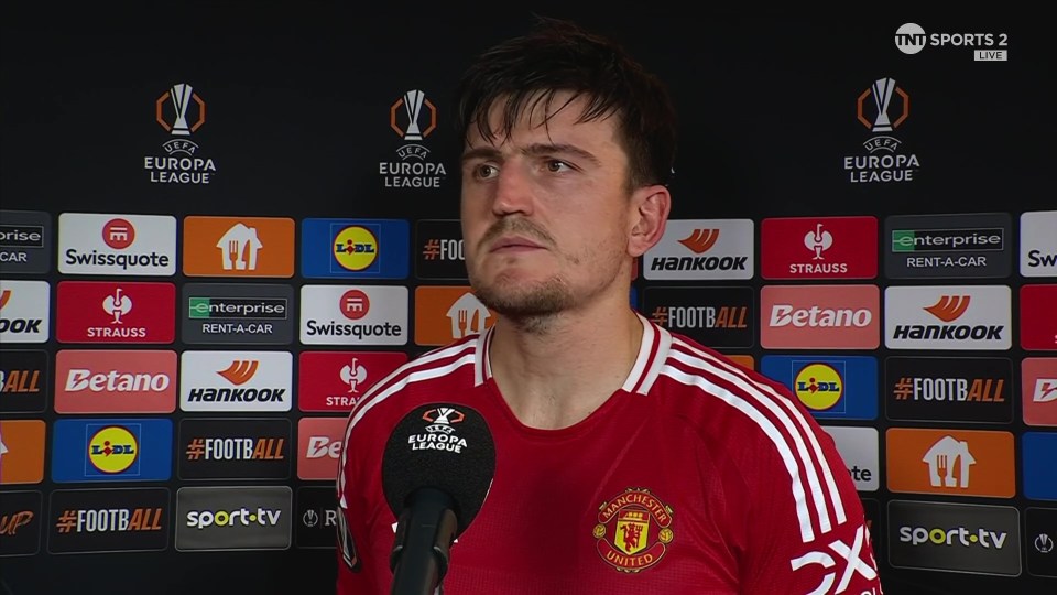 a man wearing a red manchester united jersey stands in front of a microphone