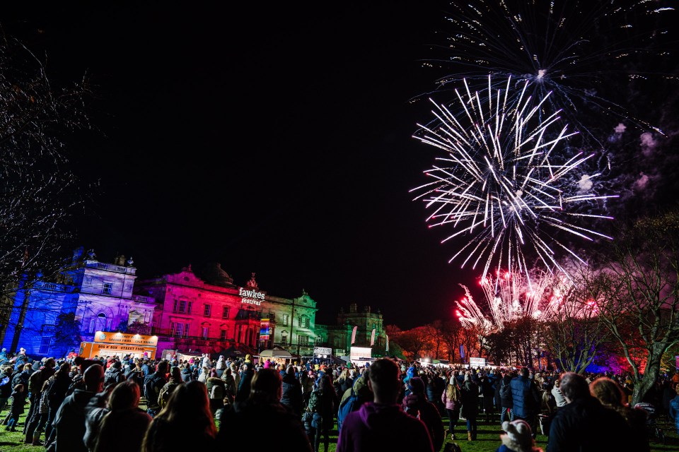 a crowd of people watching fireworks in front of a building that says fantastic