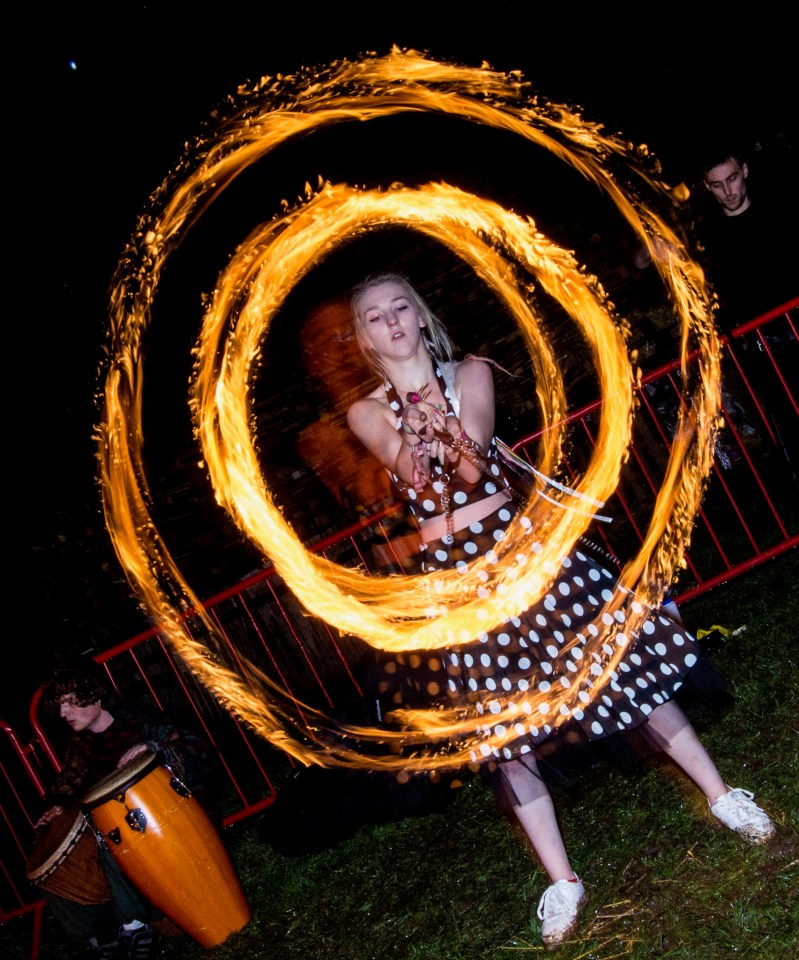 a woman in a polka dot dress is spinning a circle of fire