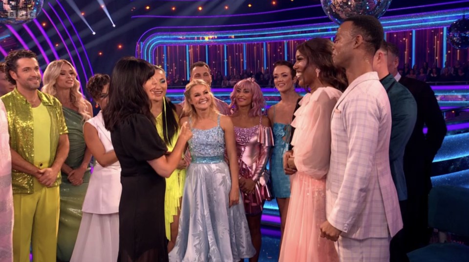 a group of people standing on a stage with a disco ball in the background