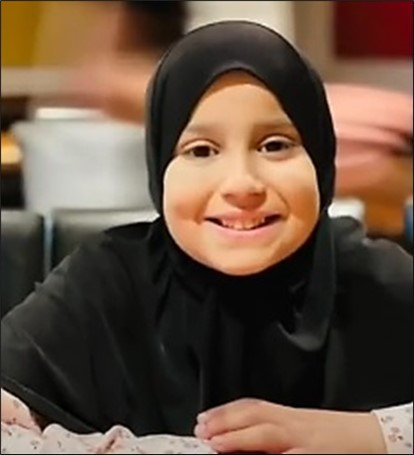 a little girl wearing a black hijab is smiling for the camera .