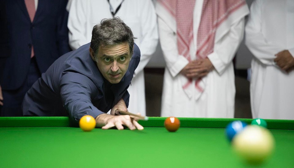 a man in a blue shirt is playing pool