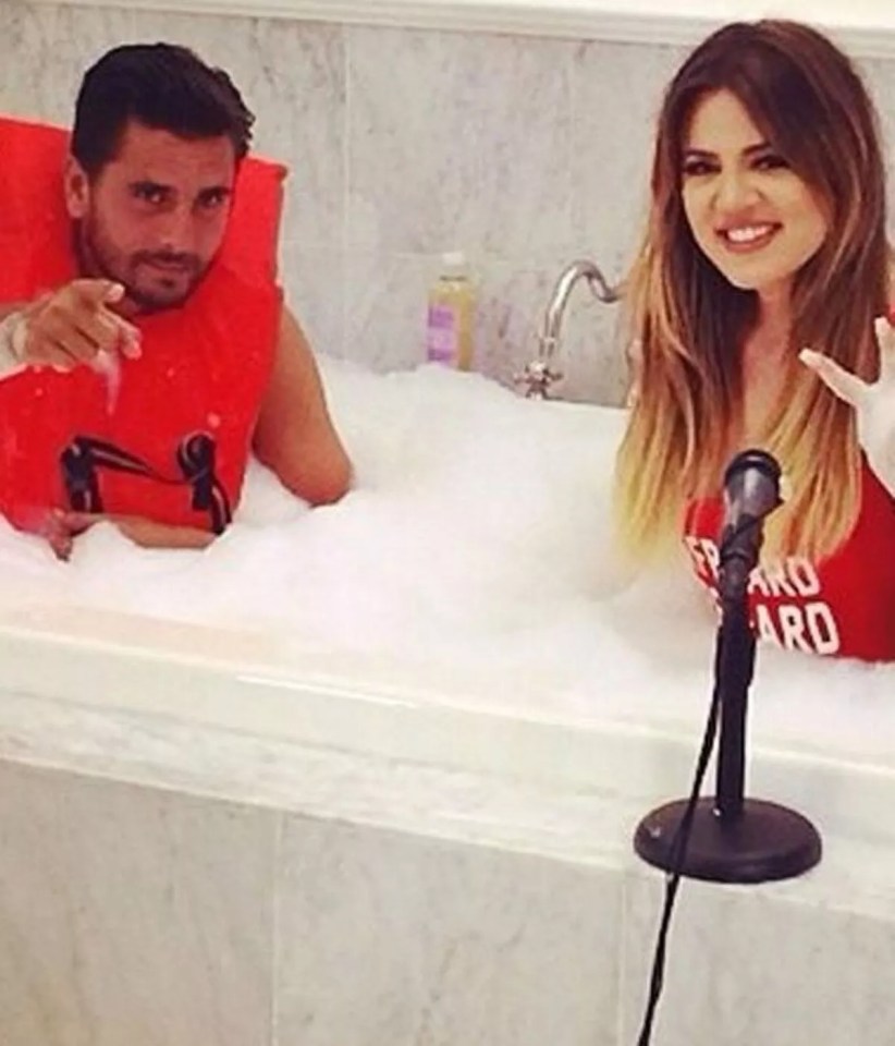 a man and a woman are sitting in a bathtub with a microphone .