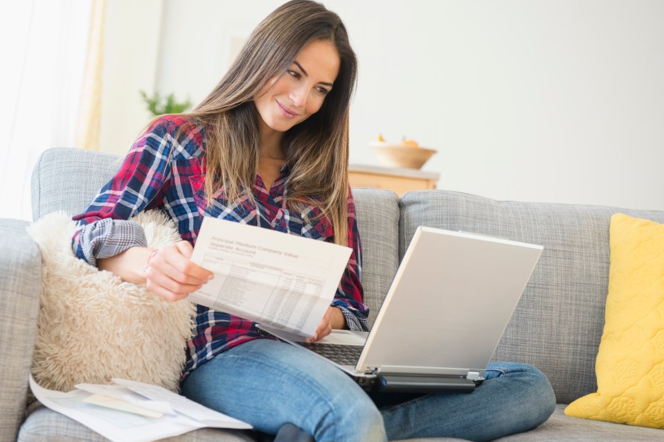 a woman sits on a couch looking at a financial statement