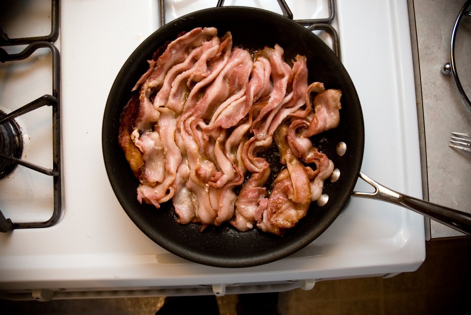 bacon is being cooked in a frying pan on a stove