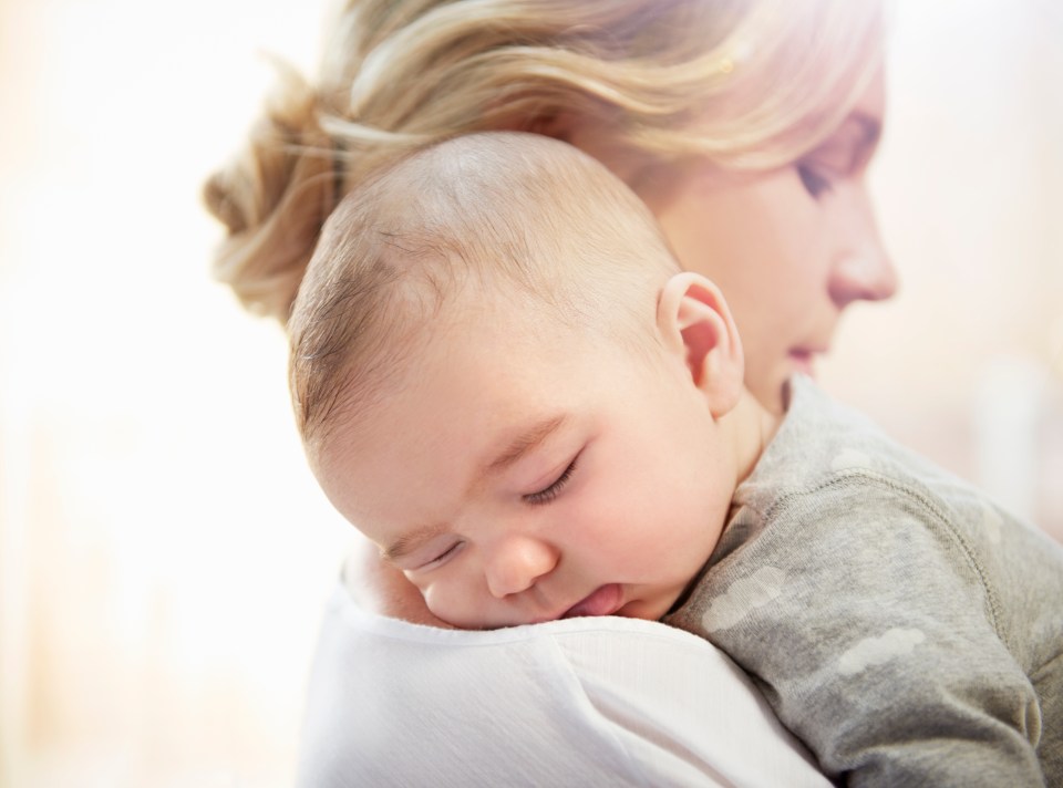 a woman is holding a sleeping baby in her arms