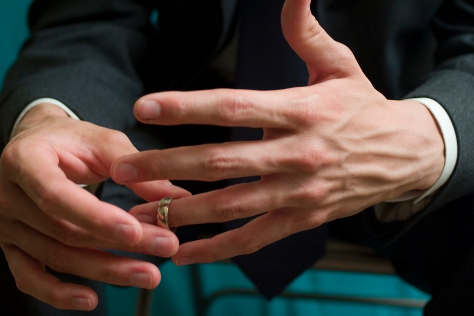 a man in a suit is taking off his wedding ring