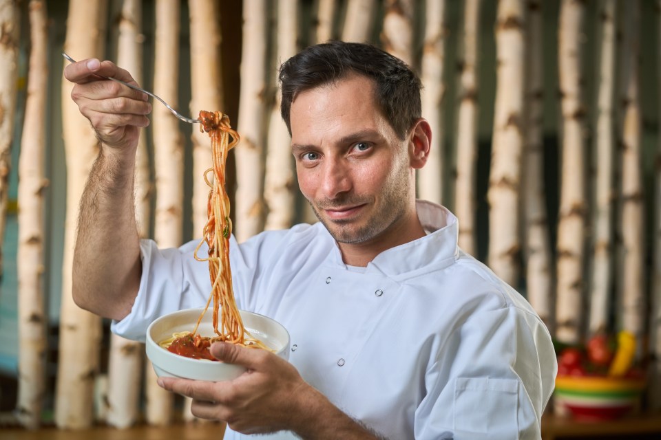 a man is holding a bowl of spaghetti and a fork