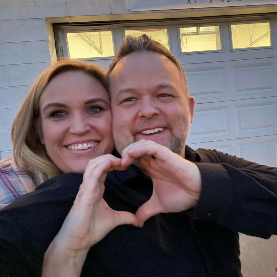 a man and woman are making a heart shape with their hands