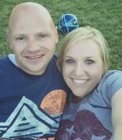 a man and a woman are posing for a picture with a soccer ball in the background