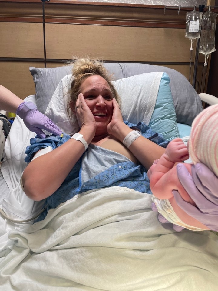 a woman is laying in a hospital bed holding a newborn baby