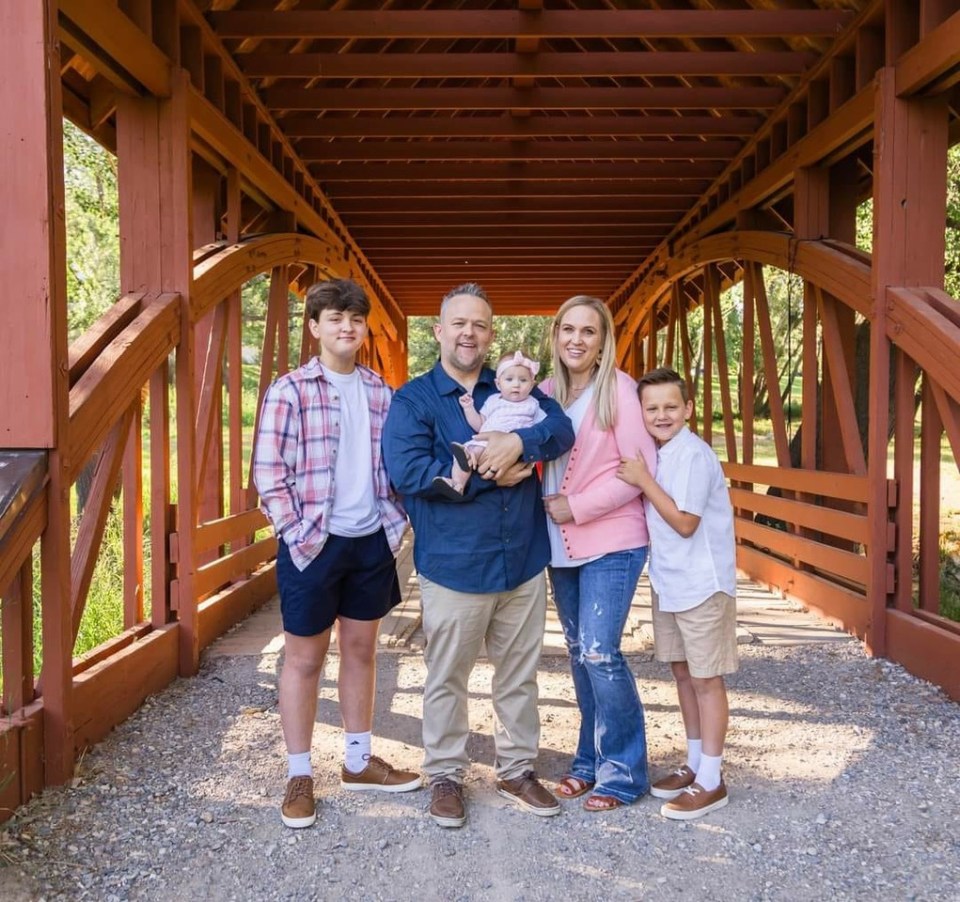 a family poses for a picture in front of a wooden bridge