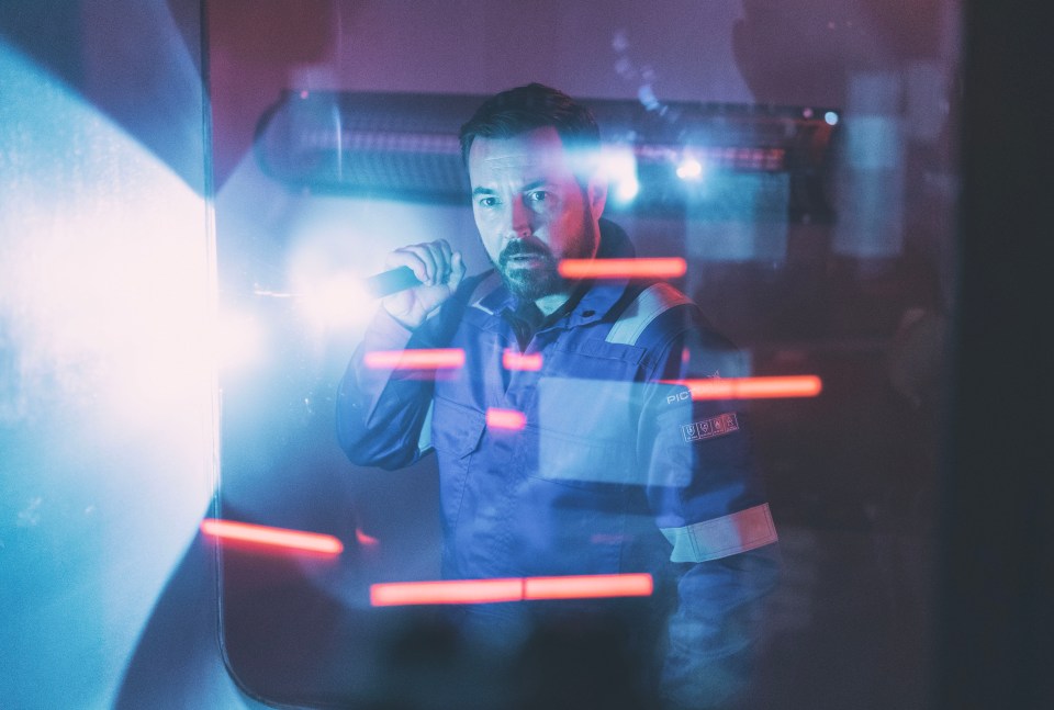 a man holding a flashlight with the word safety on his shirt