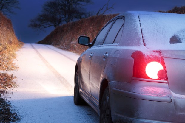 a car is parked on a snowy road at night