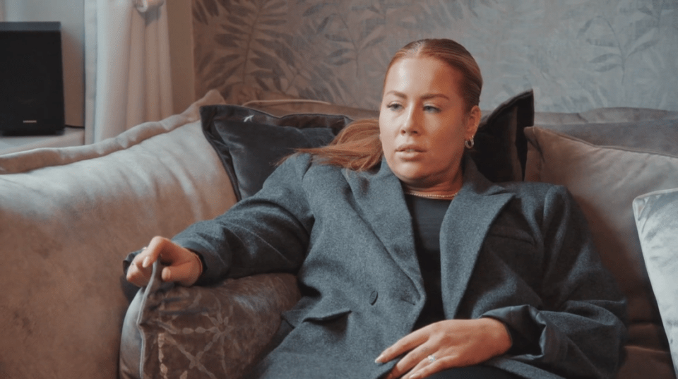 a woman in a grey jacket sits on a couch