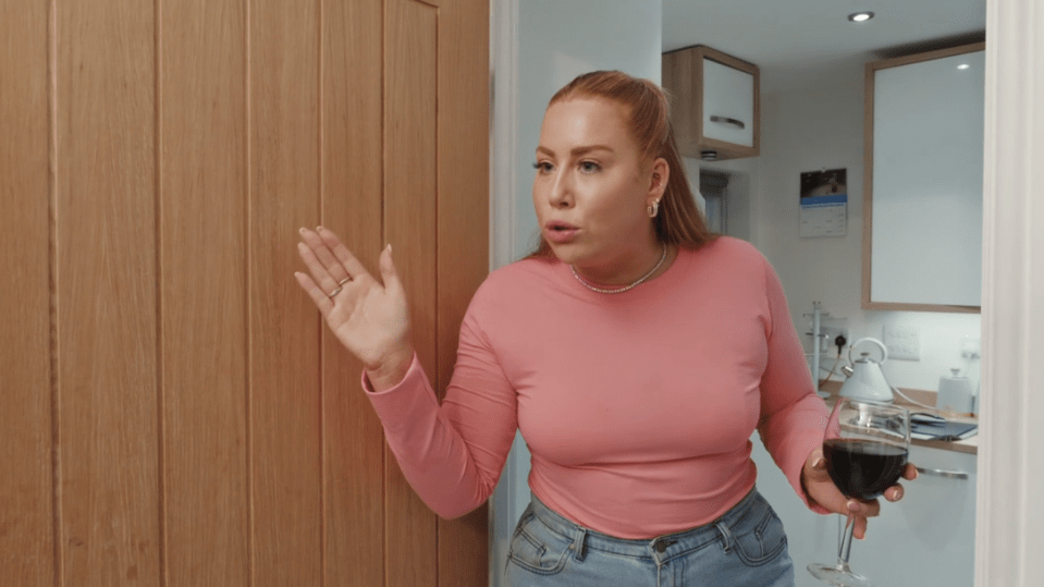 a woman in a pink shirt is holding a glass of wine