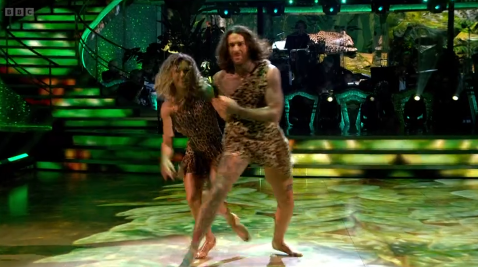 a man in a leopard print outfit is dancing with a woman